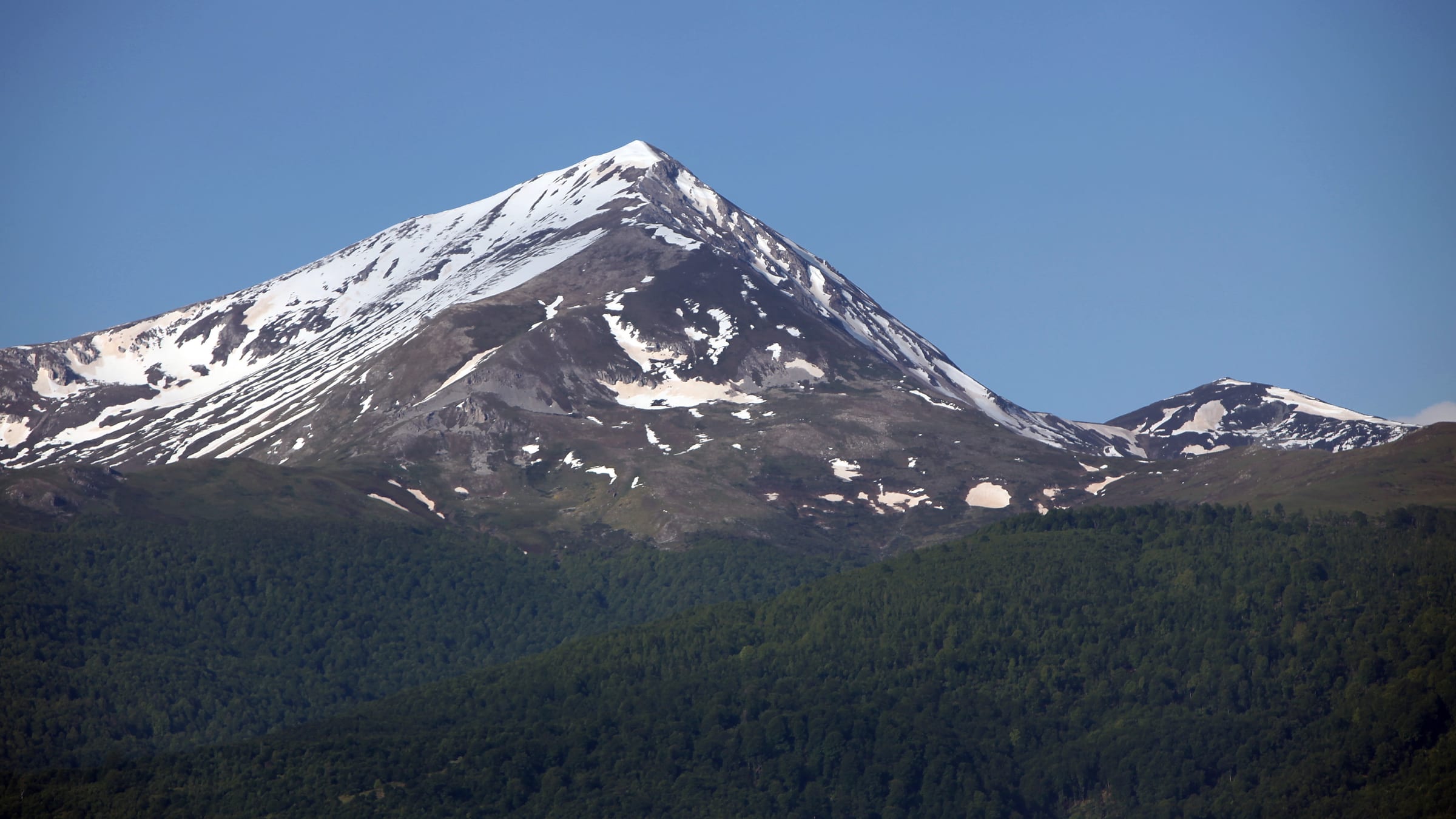La pirámide de Ljuboten, surcada de nieve, alzándose sobre el bosque oscuro en las montañas Sharr