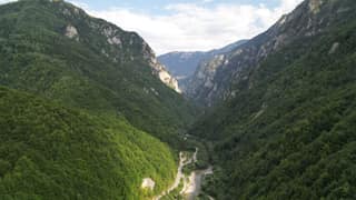 The forested Rugova Canyon from above, with the road and the Lumbardhi river threading the gorge floor