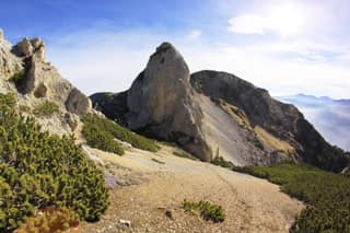 The limestone tower of Belleja above a scree path and dwarf pines, between the mountains of Irzniq and Deçan