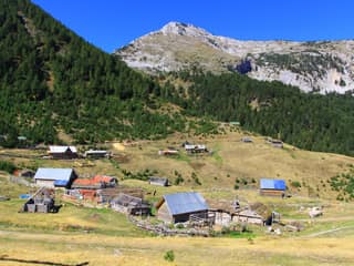 Timber shepherd huts of the Irzniq katun below a limestone peak in the mountains above Deçan