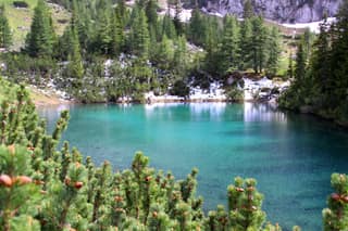 The small turquoise lake of Drelaj ringed by dwarf pine and the last spring snow in the Rugova mountains