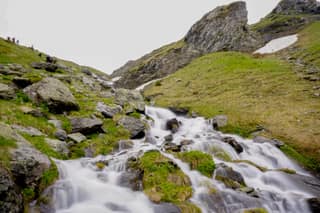 Meltwater cascading over boulders on the trail up to Gjeravica, with the last snow on the slopes above