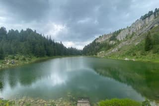 Liqenat, the glacial lake of Kuqishta in Rugova, under a storm sky with pines and cliffs on its shores