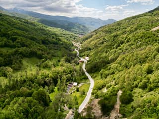 The mountain road winding through fresh spring beech forest towards Prevalla, seen from the air