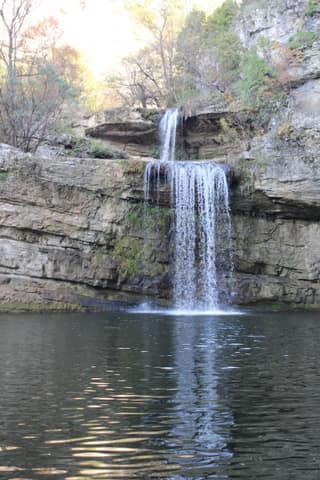 The main Mirusha waterfall dropping into its limestone pool between autumn trees